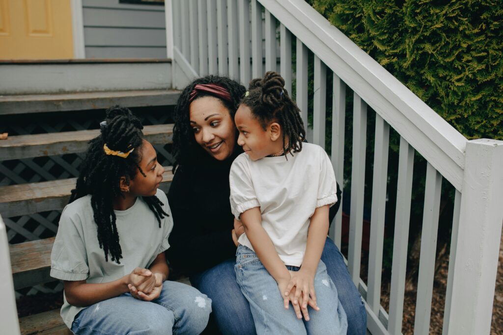 Mother with two daughters enjoying a joyful moment on the porch steps.